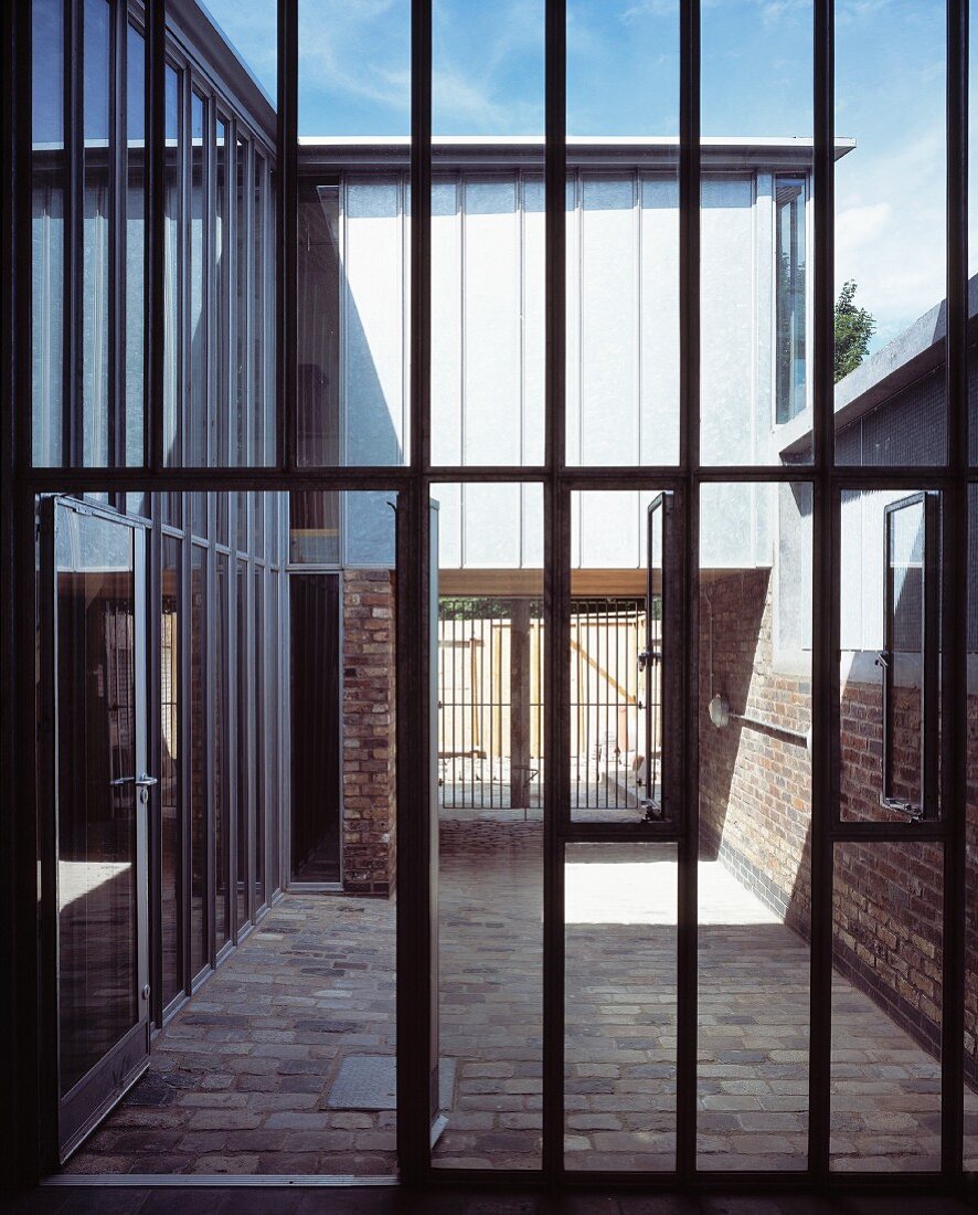 Stahlglasfassade mit offener Terrassentür und Blick in Innenhof