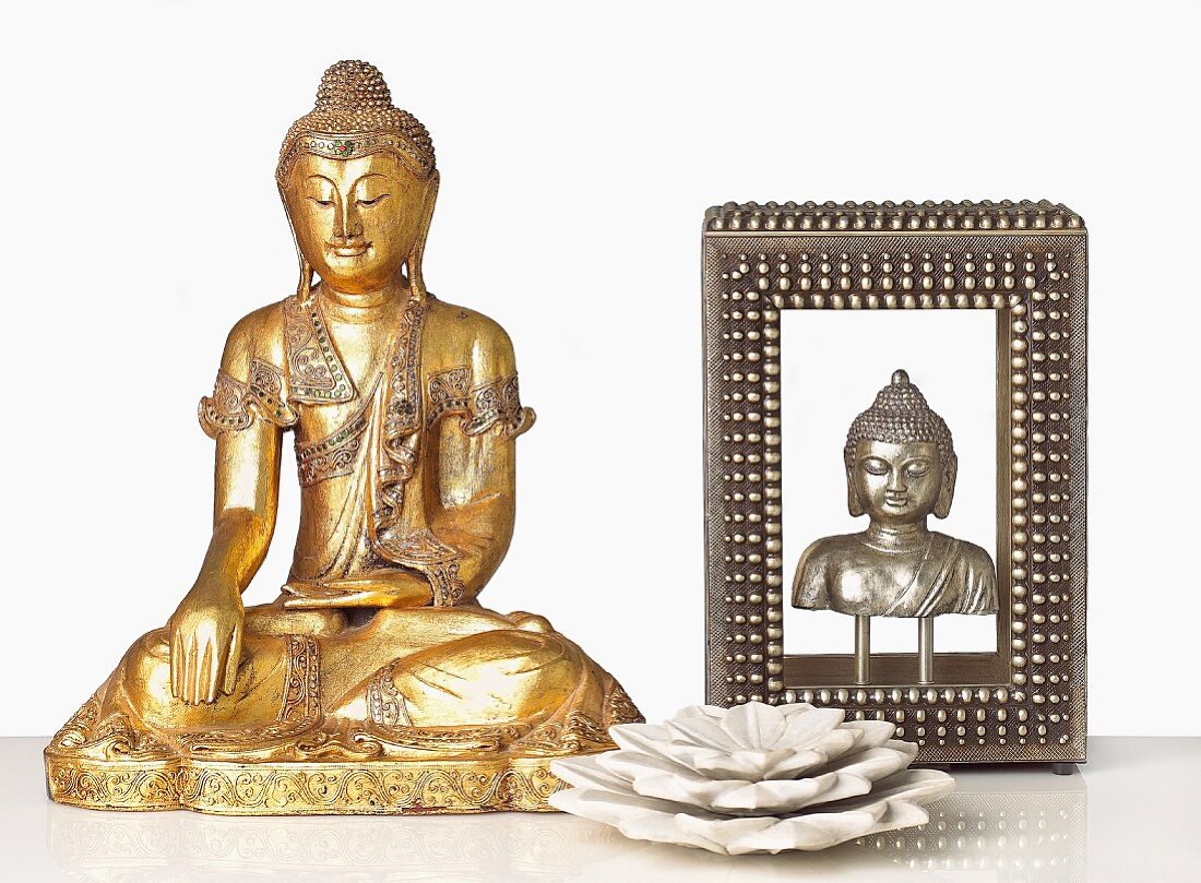 Decorative Metallic Buddahs and a Marble Lotus Flower on White Table
