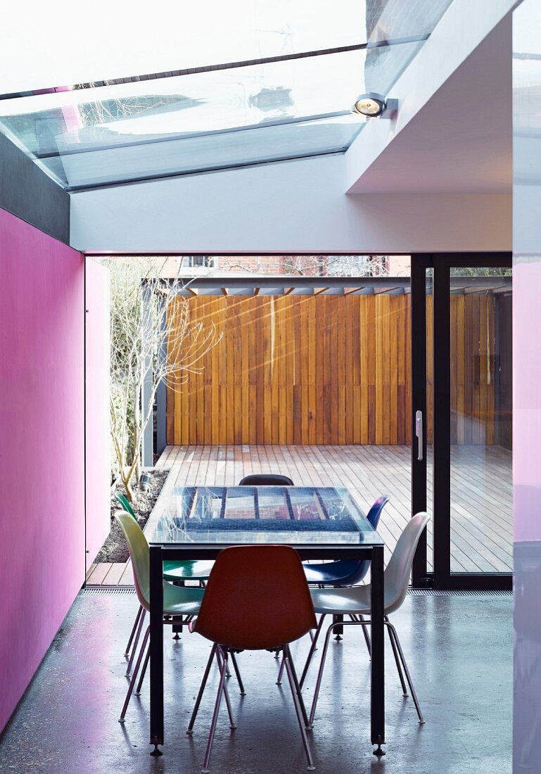 Esstisch mit Stühlen unter Oberlicht und grossflächigem Terrassenfenster