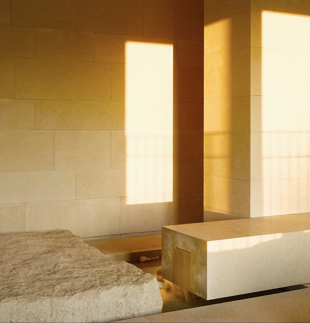 Light and shadows playing on a tiles wall and smooth block of stone next to a roughly hewn one