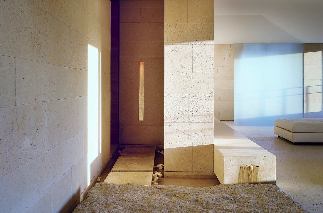 Licht- und Schattenspiele auf gefliester Wand und helle Steinbank im minimalistischem Wohnraum