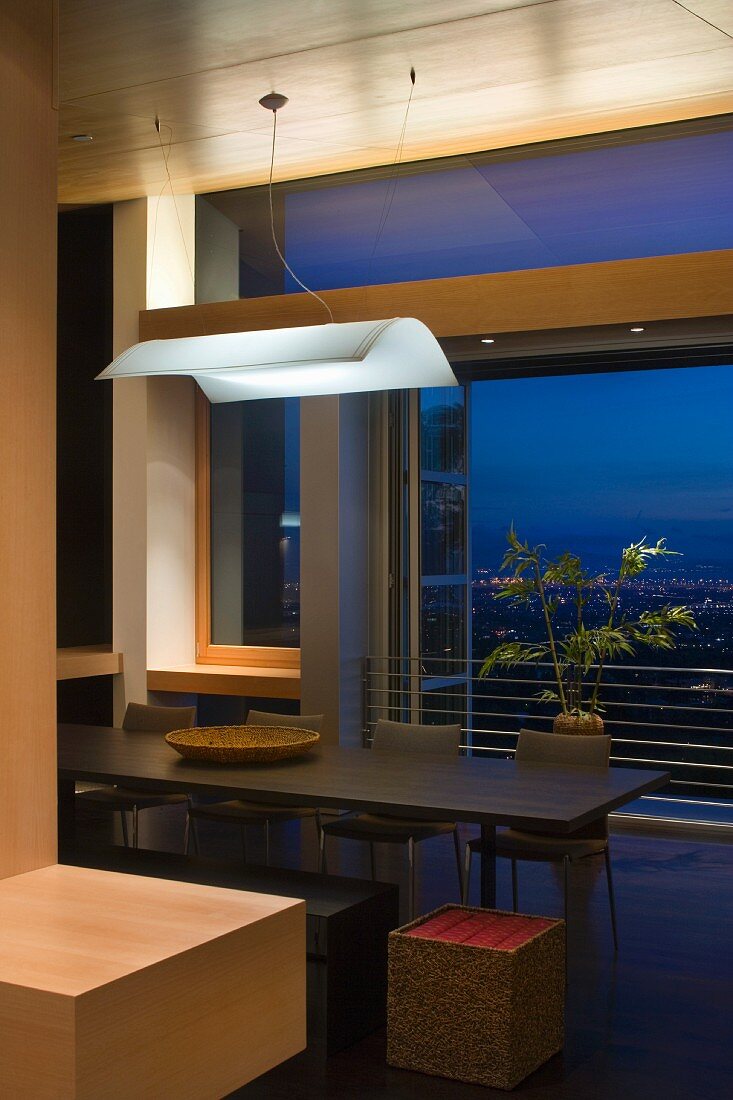 White light canopy above a dining table in front of an open French window and evening mood