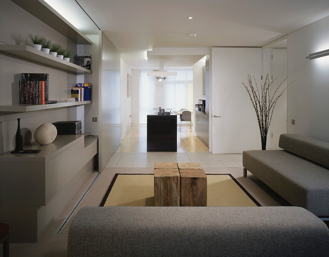 Hellgraue Sofagarnitur im modernen Wohnraum und offene Küche mit freistehendem Küchenblock