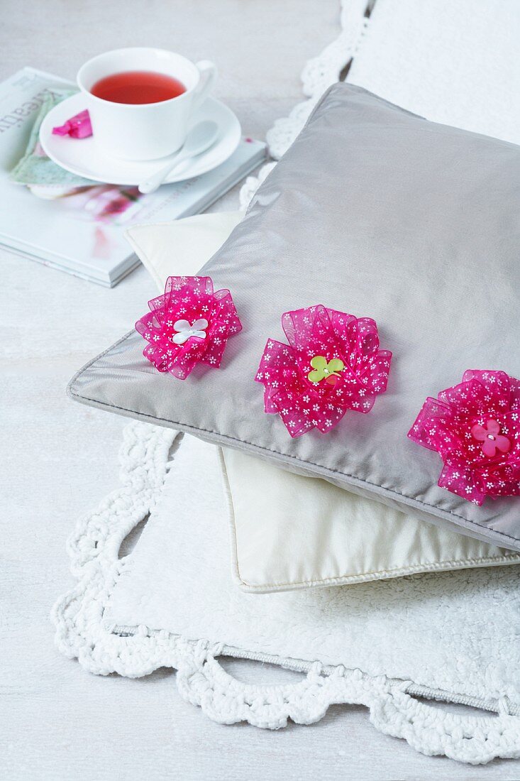 Pillows decorated with flowers on a rub next to a cup of tea
