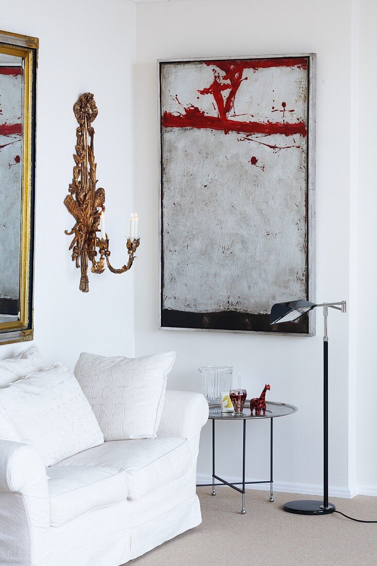 Ecke eines Wohnzimmers mit Sofa, Beistelltisch, Wandkerzenhalter und Gemälde