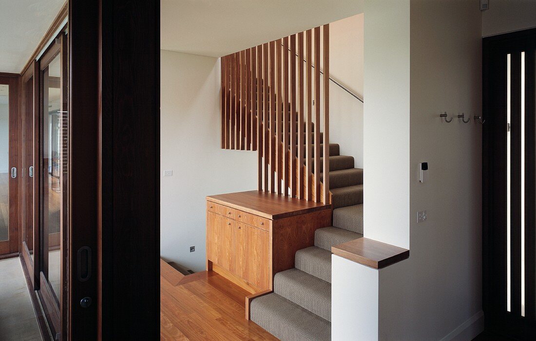 Stairway with built in chest of drawers and transparent wall made of wooden louvers
