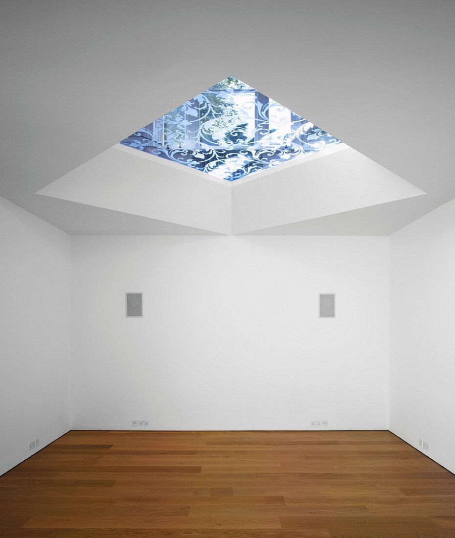 An empty room with a parquet floor and a skylight