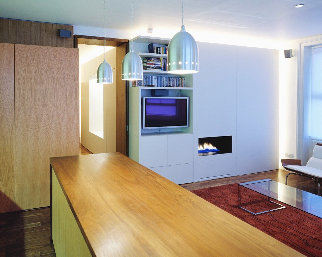 Küchentheke aus Holz mit modernen Hängelampen aus Edelstahl im offenen Wohnraum