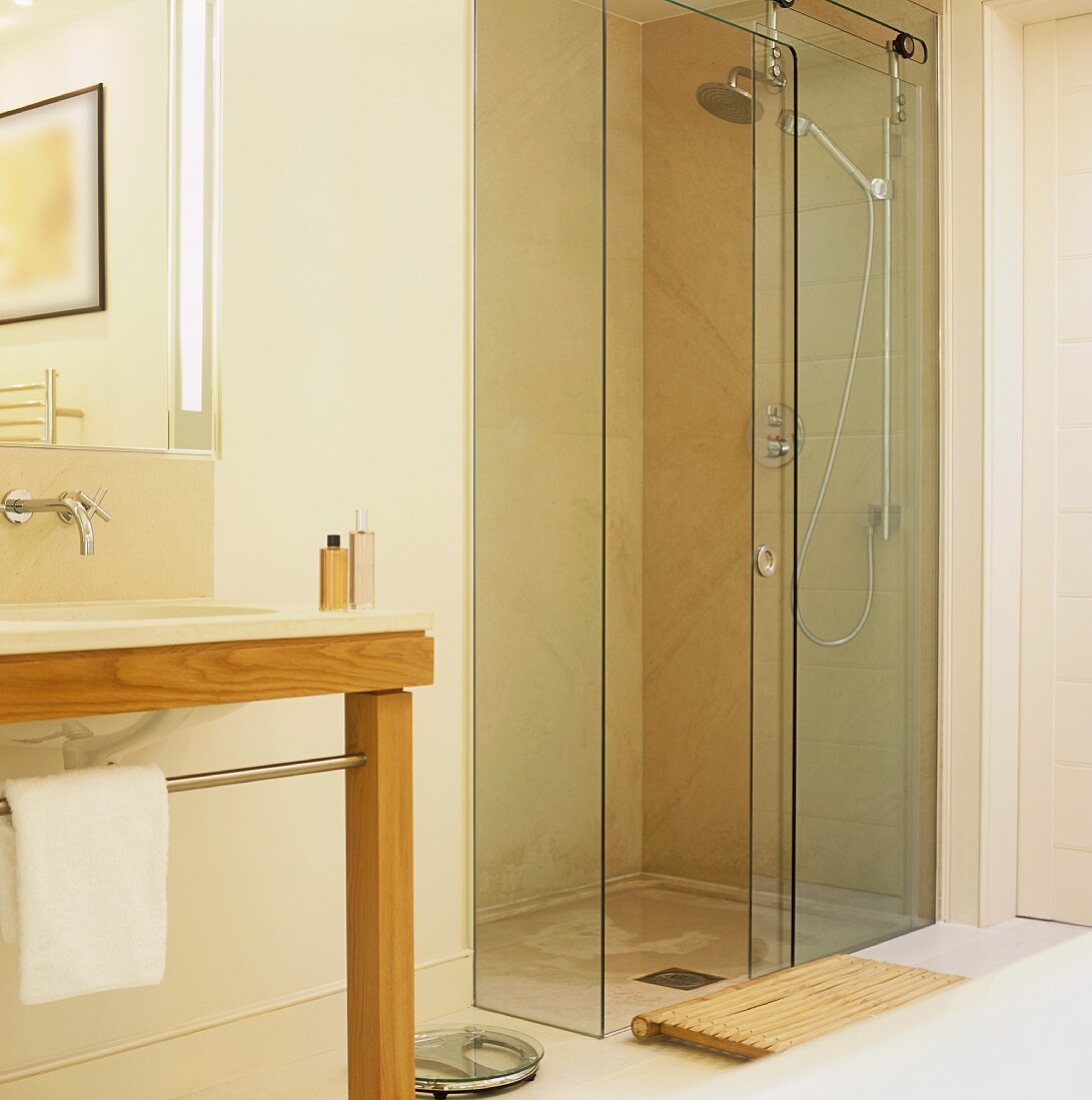 A walk-in shower with a glass door and a wash stand