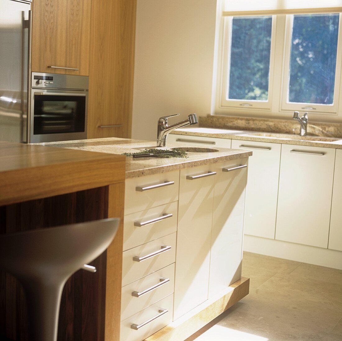 A free-standing sink with white cupboards underneath and a wooden counter in a contemporary kitchen