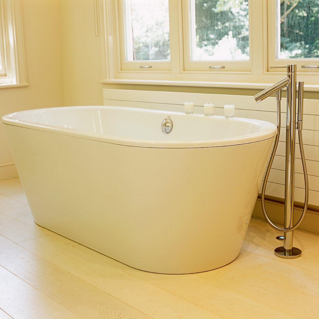 weiße freistehende Badewanne auf hellem Dielenboden mit Designer Standarmatur