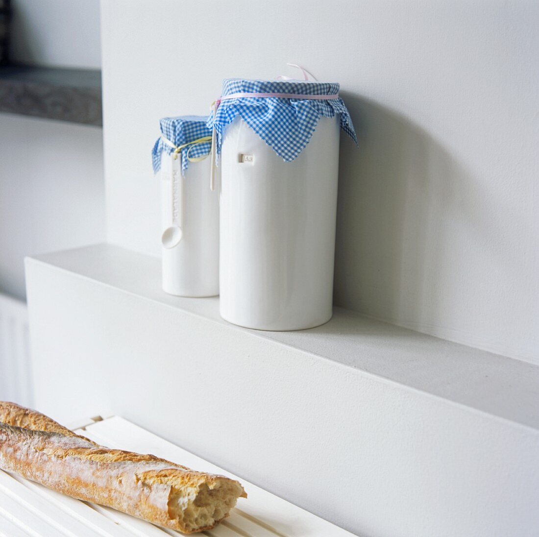 White storage jars with blue and white checked fabric lids