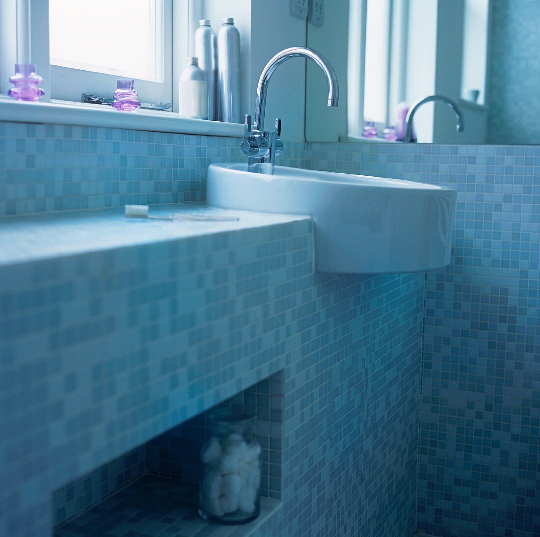 Waschbecken unter dem Fenster in einem Badezimmer mit Mosaikfliesen