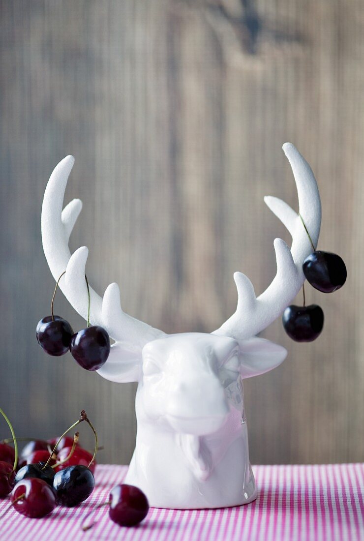 Sweet cherries hanging on the antlers of a porcelain stag