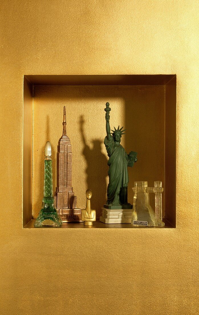 Amerikanische Miniatur Freiheitsstatue neben Miniatur-Häuser in gold getönter Wandnische