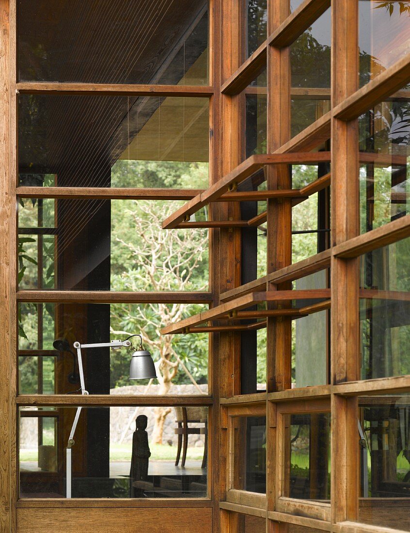 Blick durch Holzglasfassade mit geöffneten Fenstern im traditionellen Stil auf Retro-Tischlampe aus Edelstahl