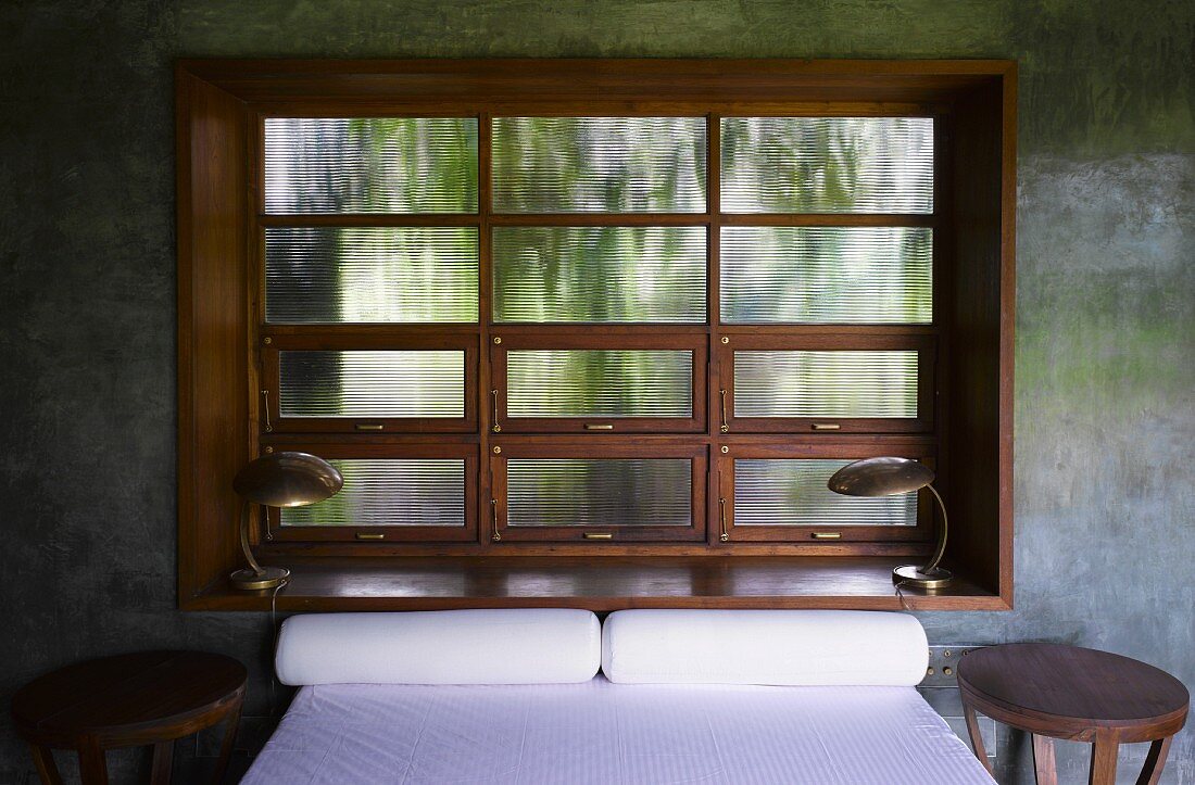 Double bed in front of traditional lattice window in concrete wall
