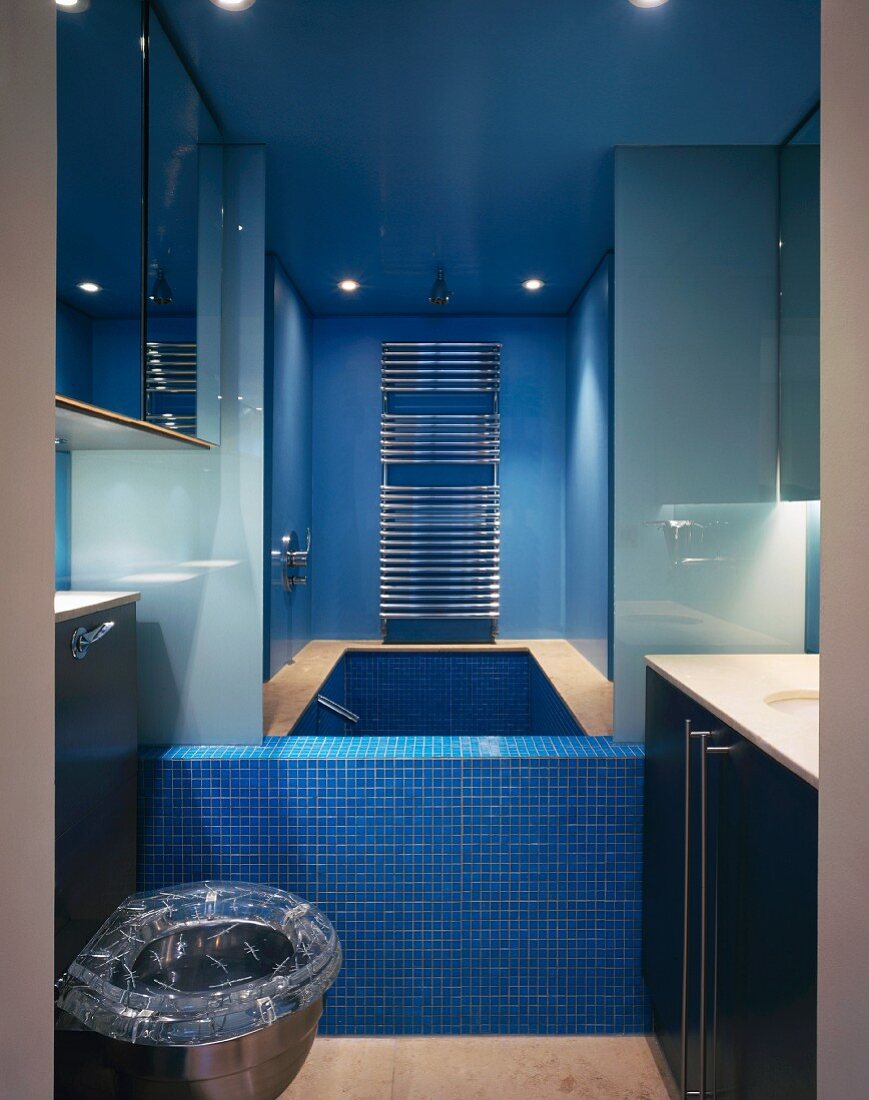 Small, modern bathroom with built-in bathtub and blue mosaic tiles
