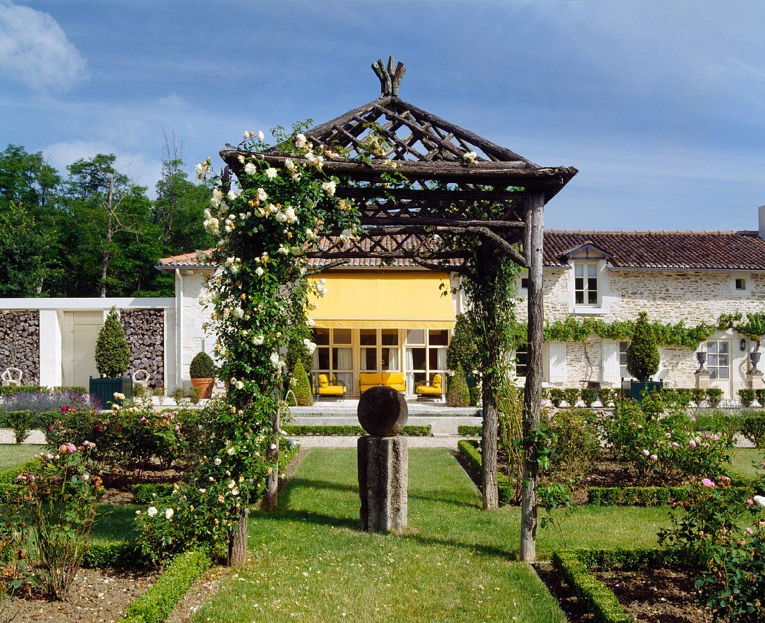 Rustic, Asian style pergola in a landscaped garden in front of a country home
