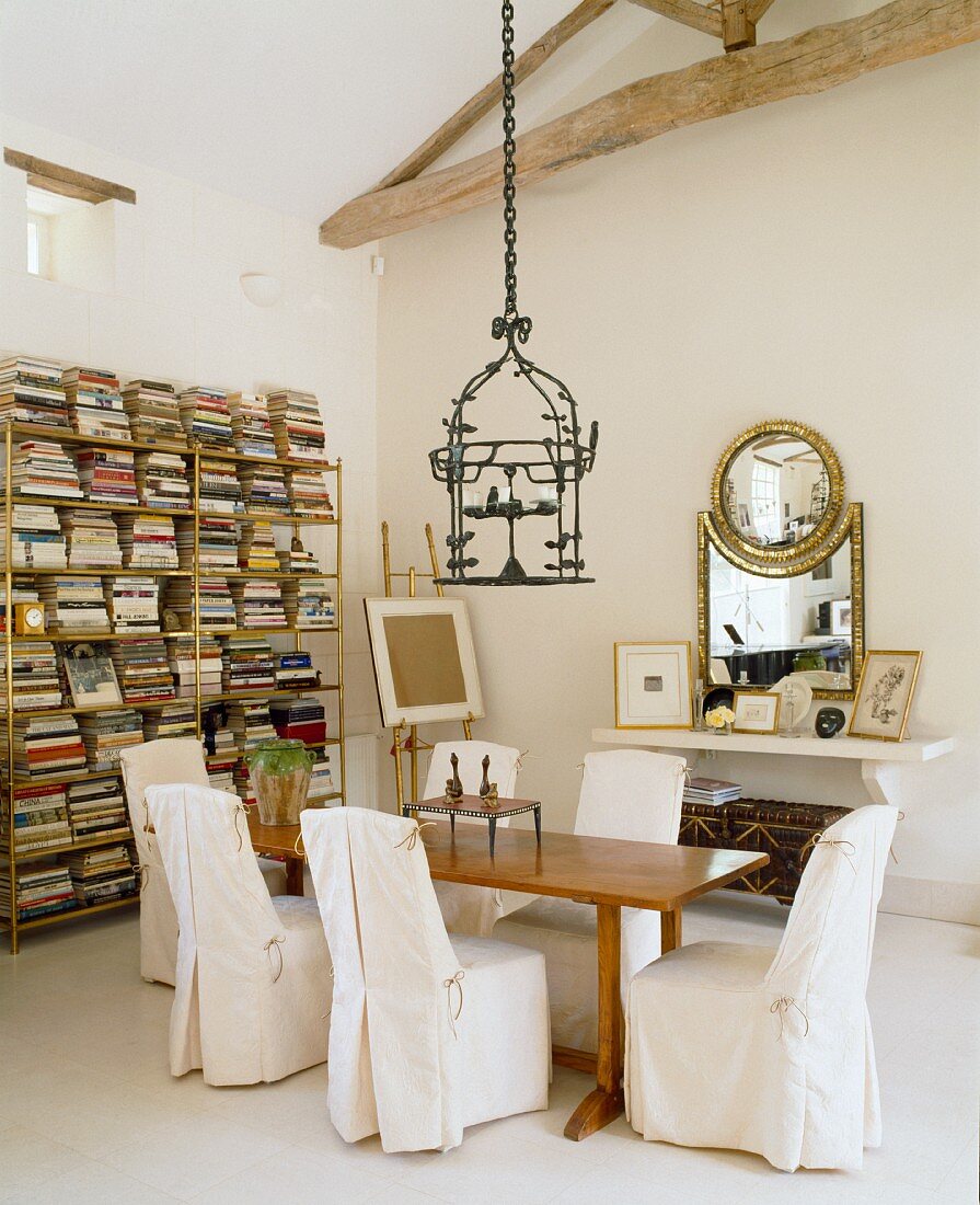 Chairs with white covers at a rustic table in a library corner