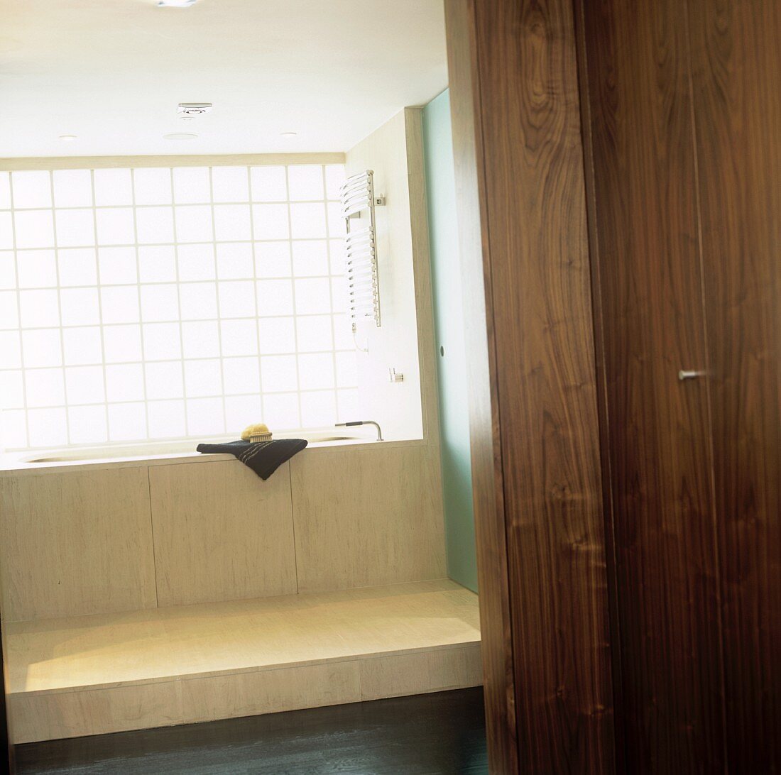 Blick durch offene Tür auf Badewanne und Podest aus hellem Holz