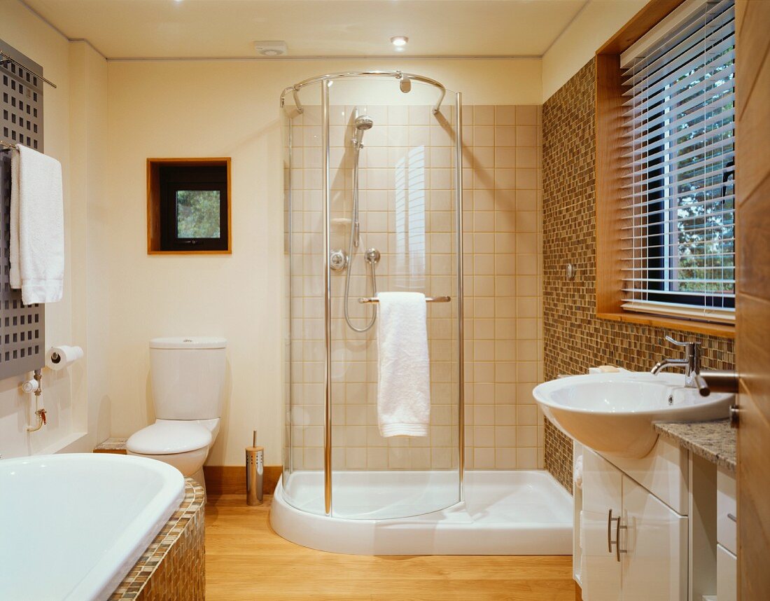 Grosszügiges Bad mit gebogener Glastür im Duschbereich und Waschtisch vor Fenster