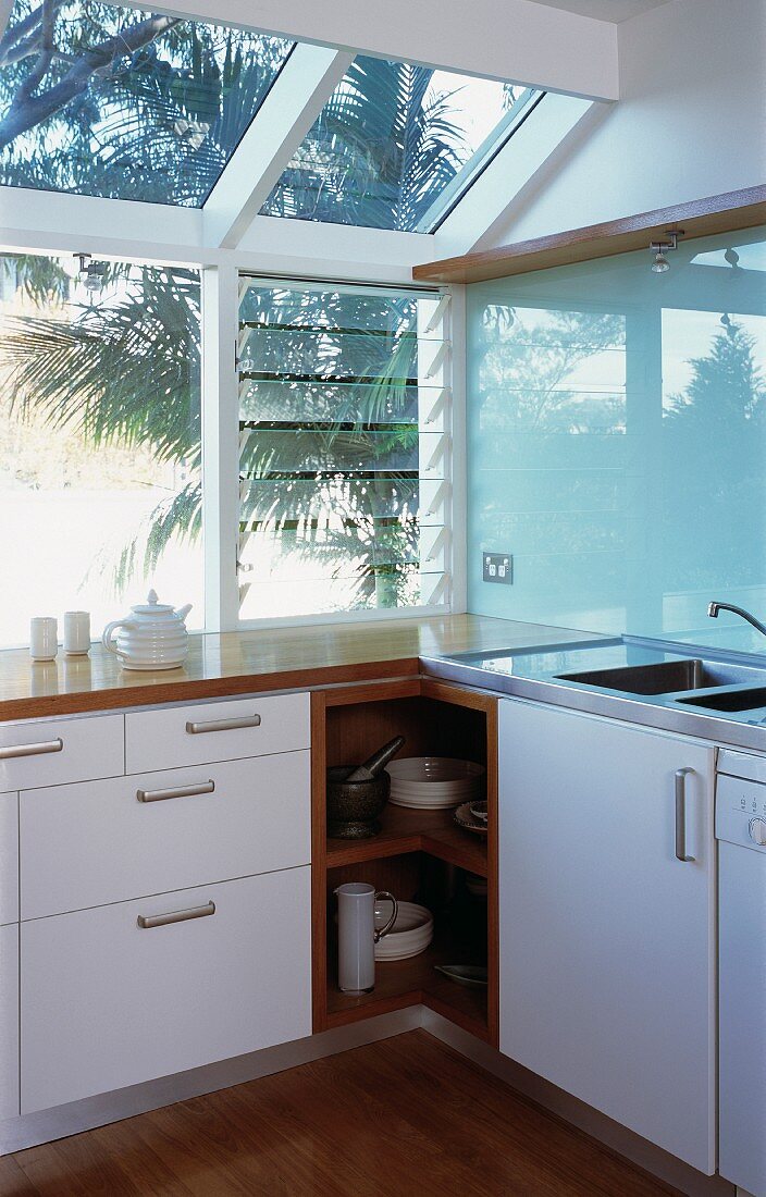Moderne Küchenecke vor Fenster mit geöffneten Glaslamellen
