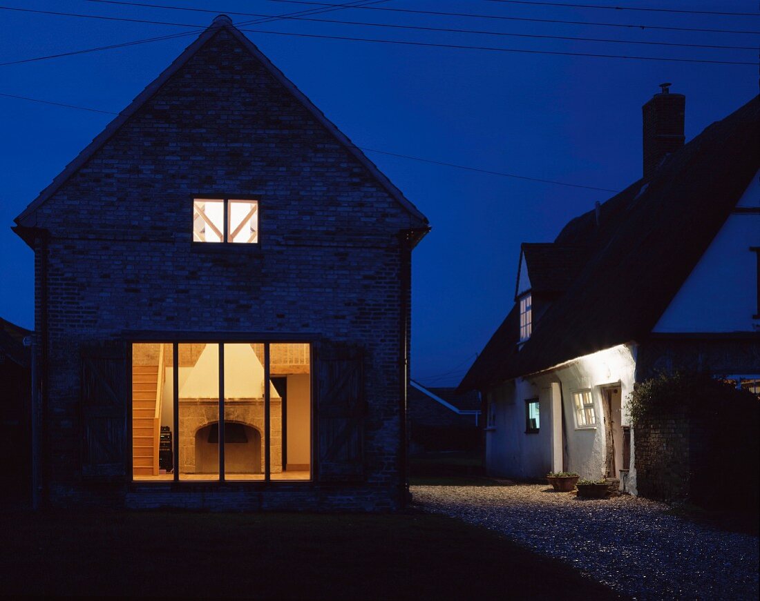 Renoviertes Einfamilienhäuschen in Nachtstimmung mit beleuchteten Fenstern und Blick auf Kamin