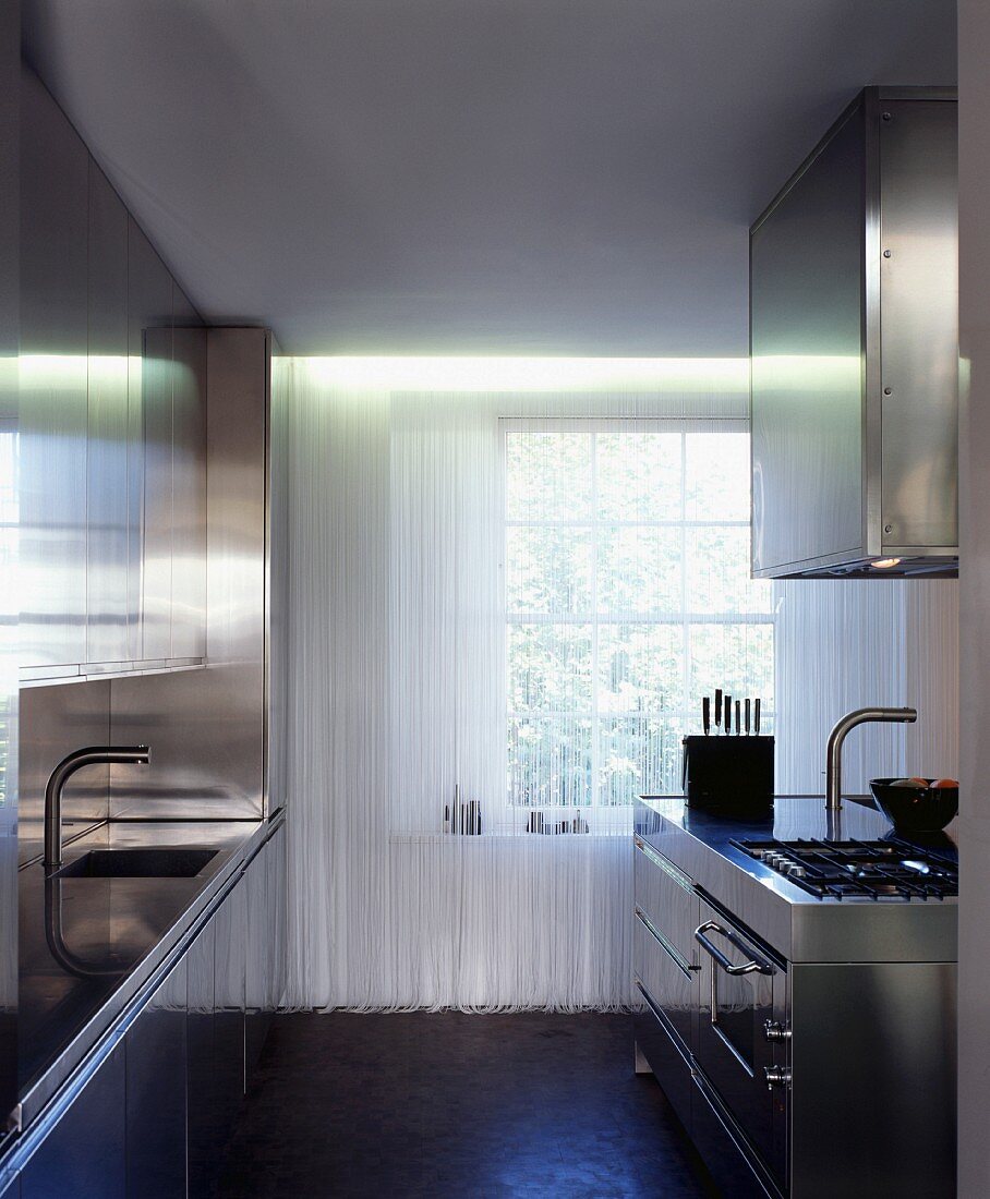 Cord curtain in front of lattice window in minimalist stainless steel kitchen with two worktops