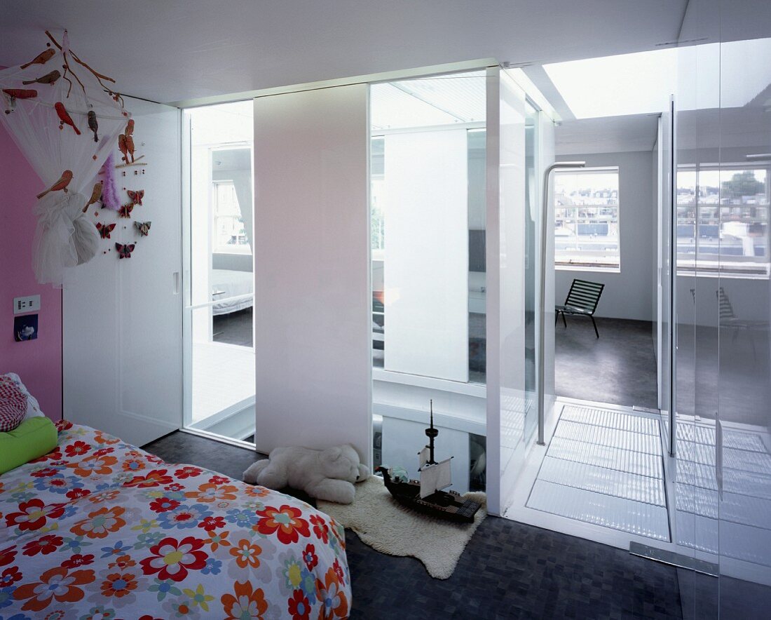 Blumige Bettwäsche in Kinderzimmer mit Blick durch raumhohe Fensterstreifen in Treppenraum und Wohnzimmer