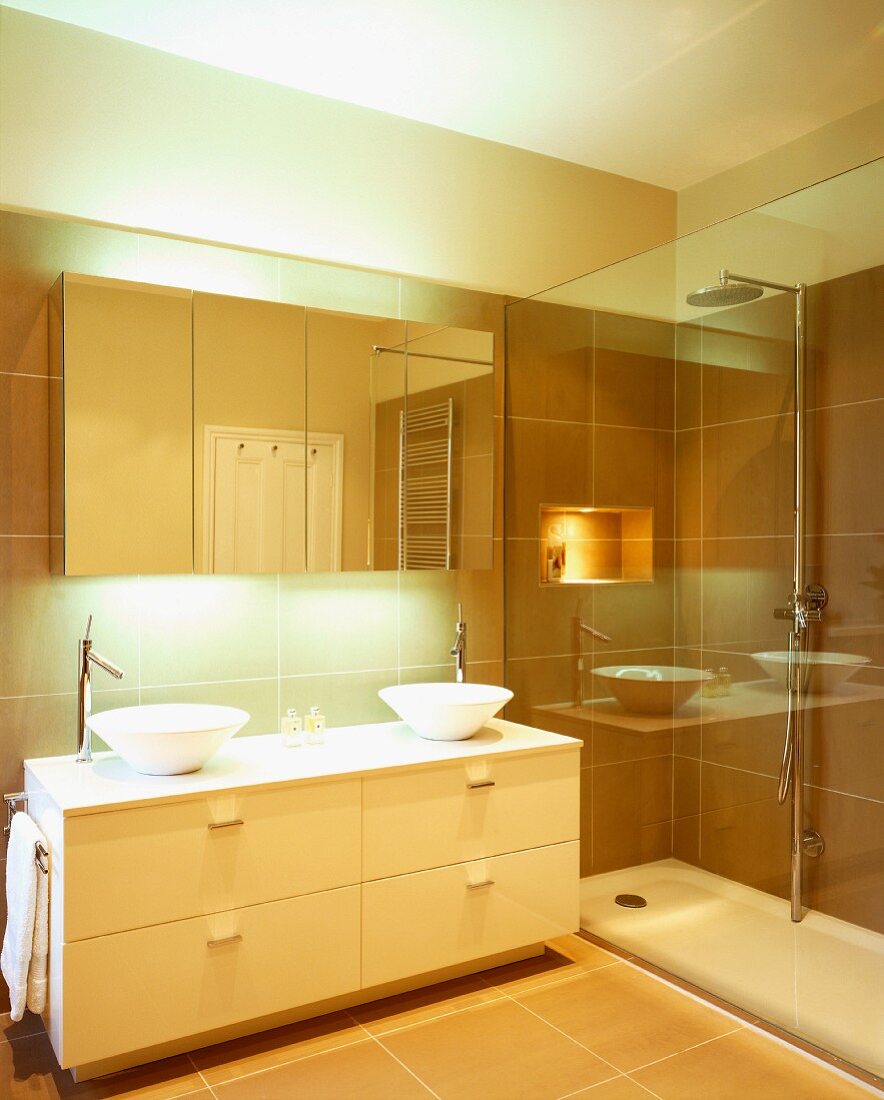 Spiegelungen auf Glaswand vor Dusche und Spiegelschrank in modernem Bad mit zwei runden Aufsatzbecken