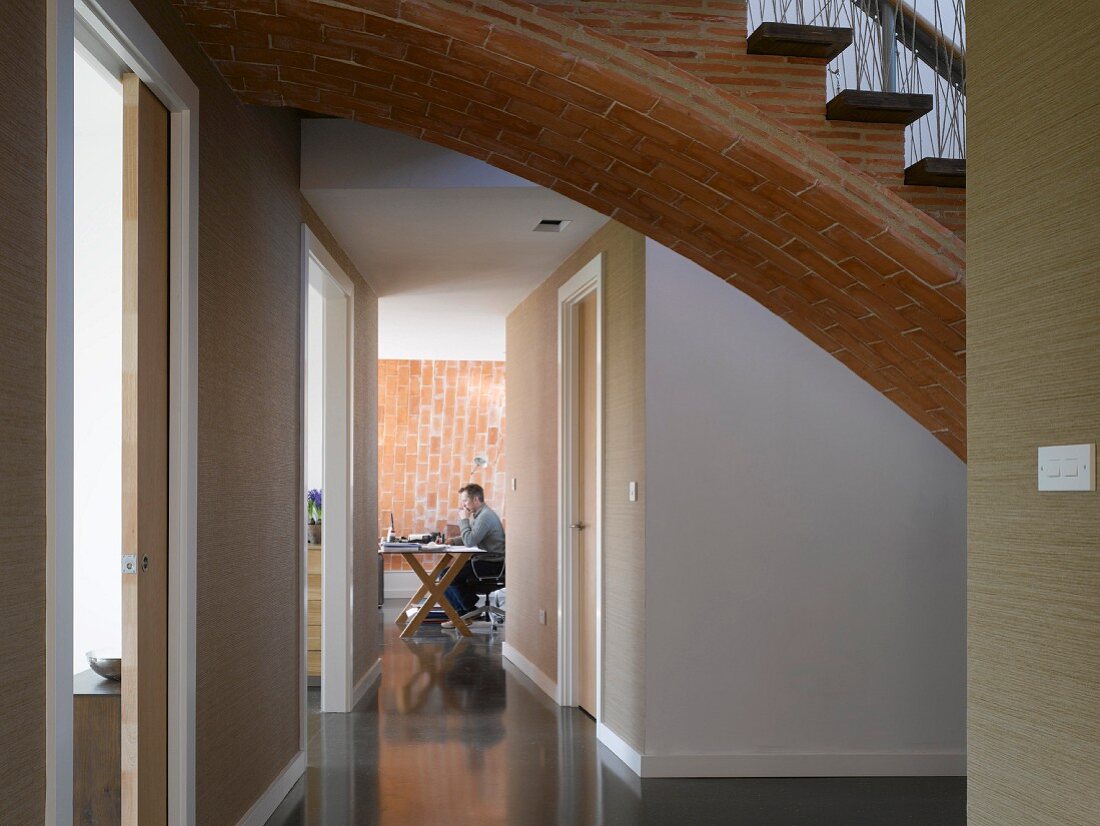 Gewölbte Ziegeltreppe mit Holzstufen über Gang zum Arbeitszimmer mit Backsteinwand