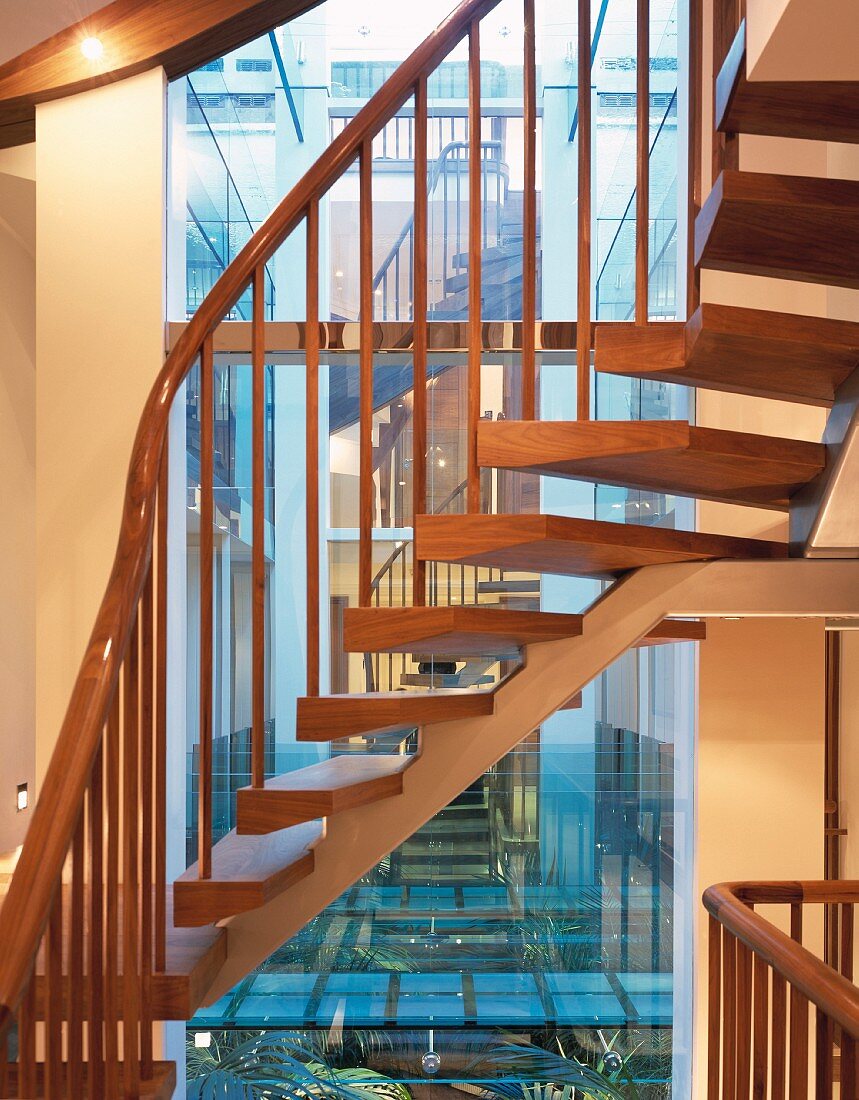 Offene Wohnungstreppe mit Holzstufen auf Metallkonstruktion vor spiegelnder Fensterfläche