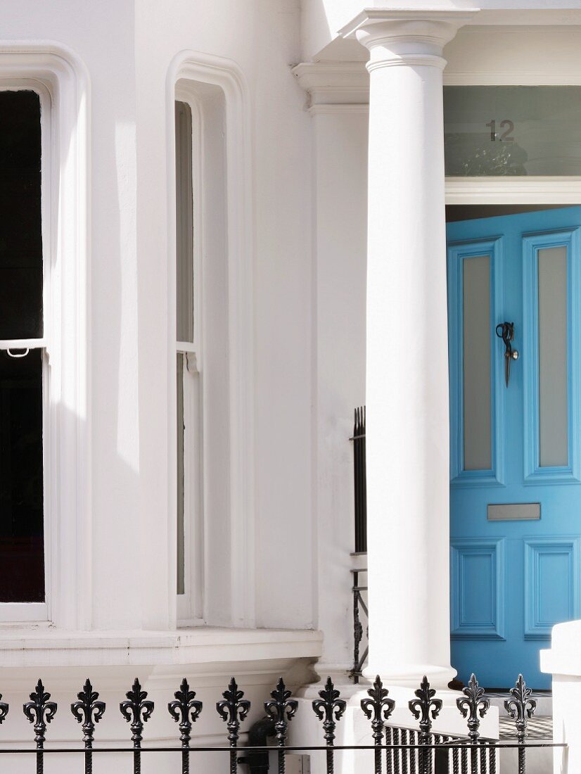 Front door to English villa with Greek columns and light-blue door