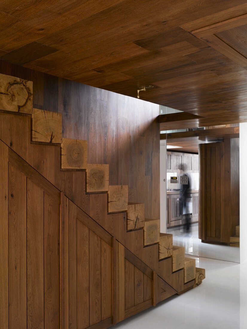 Holztreppe mit Stufen aus Vierkantholz im offenen Vorraum mit holzverkleideten Wänden und Decke