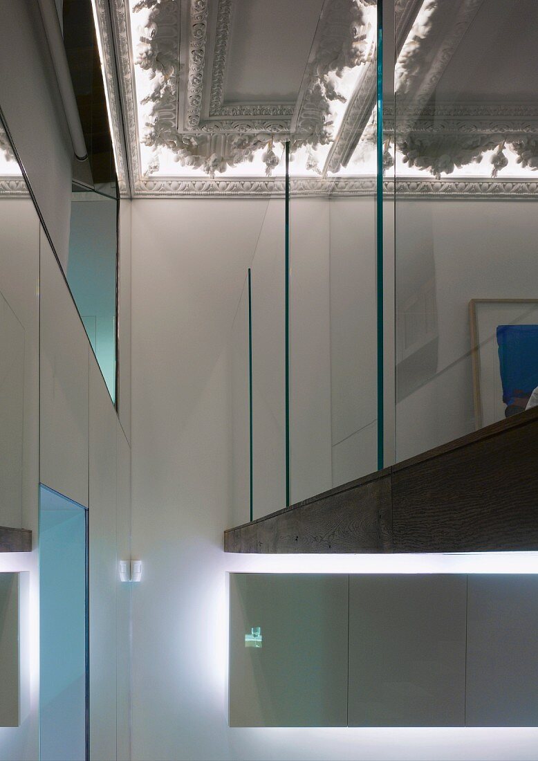 Galerie mit Glaswand unter indirekt beleuchteter Stuckdecke im Vorraum einer Villa