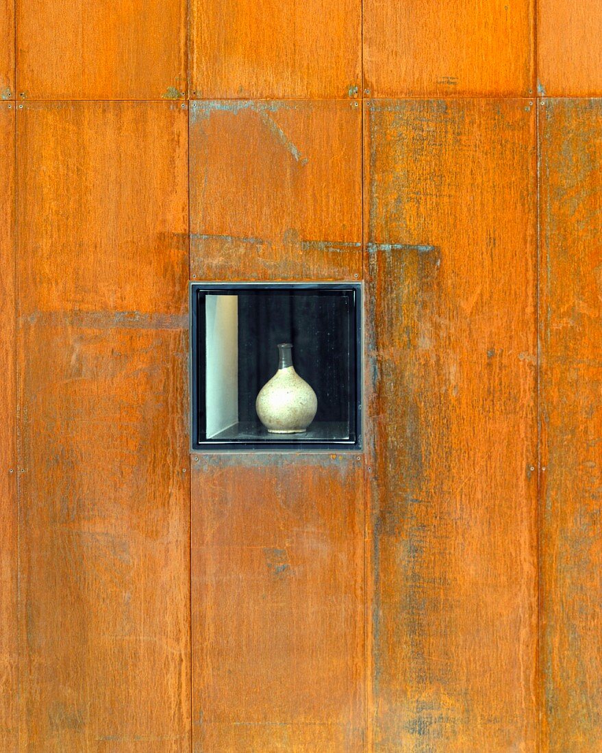 Verwitterte Holzwand mit handgemachter Vase in Wandnische