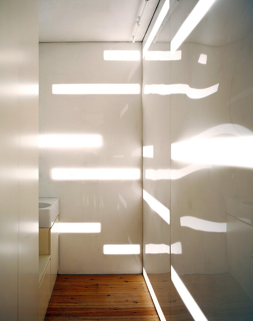 Bathroom with illuminated bands and reflections on white painted glass wall