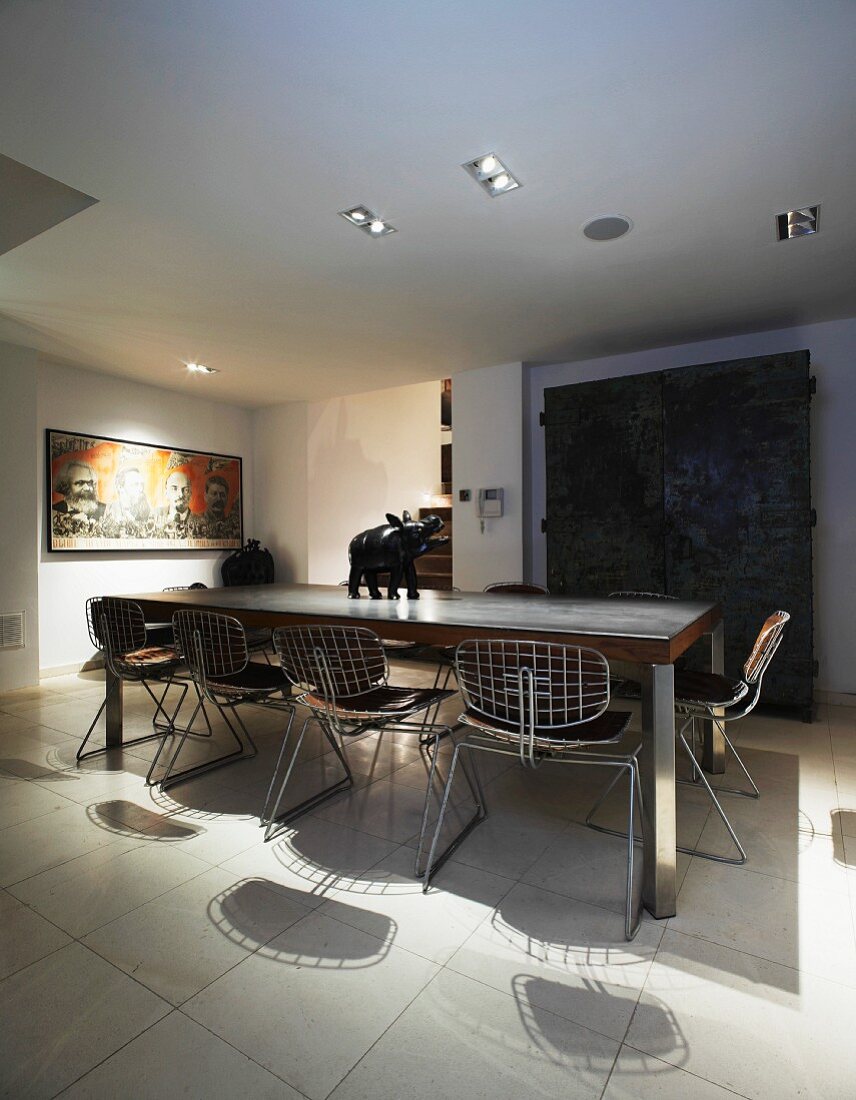 Moderner Esstisch mit Stühlen aus gitterartigem Metallgestell auf weißem Fliesenboden