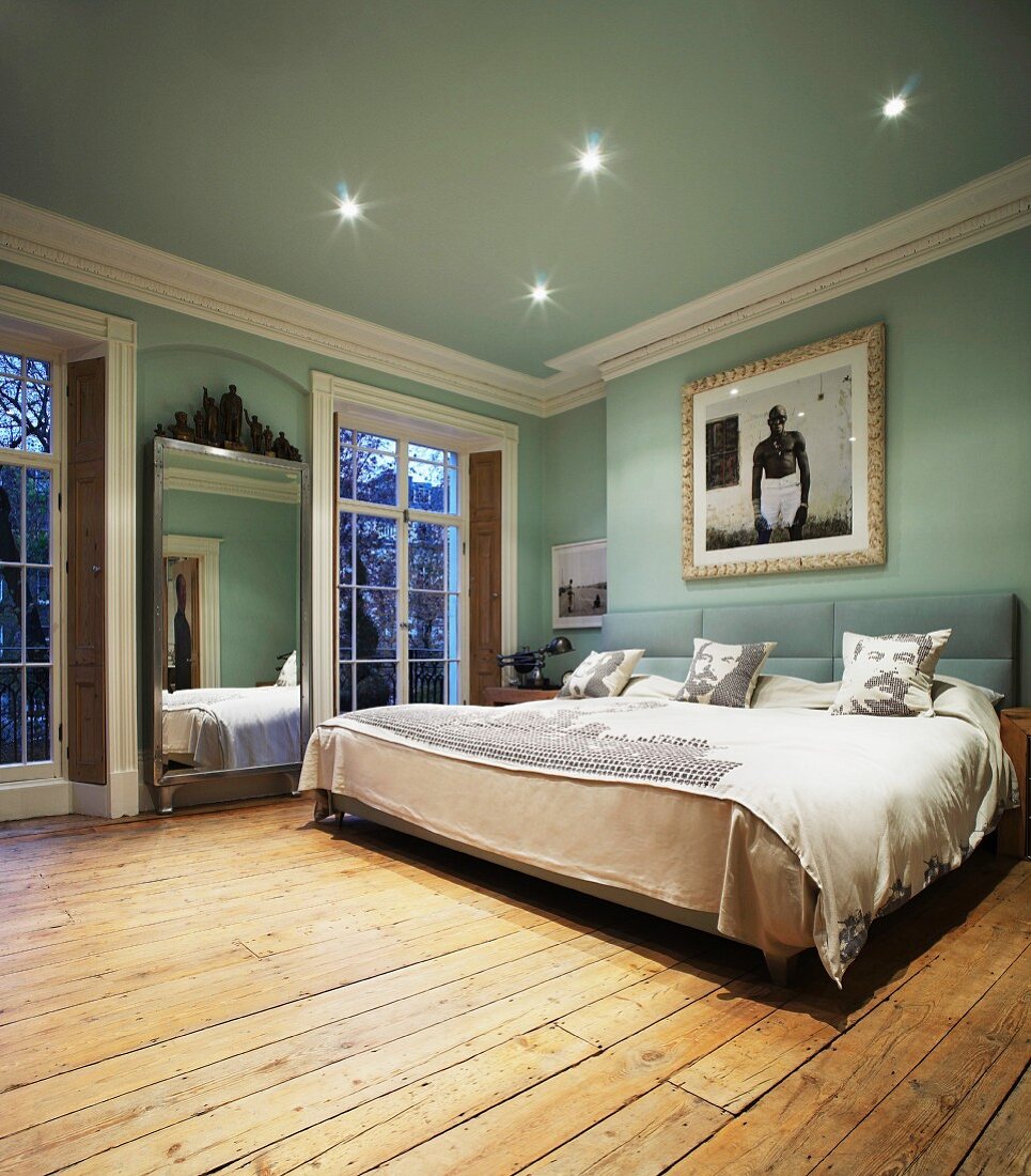 Modern double bed and rustic floorboards in traditional light blue bedroom