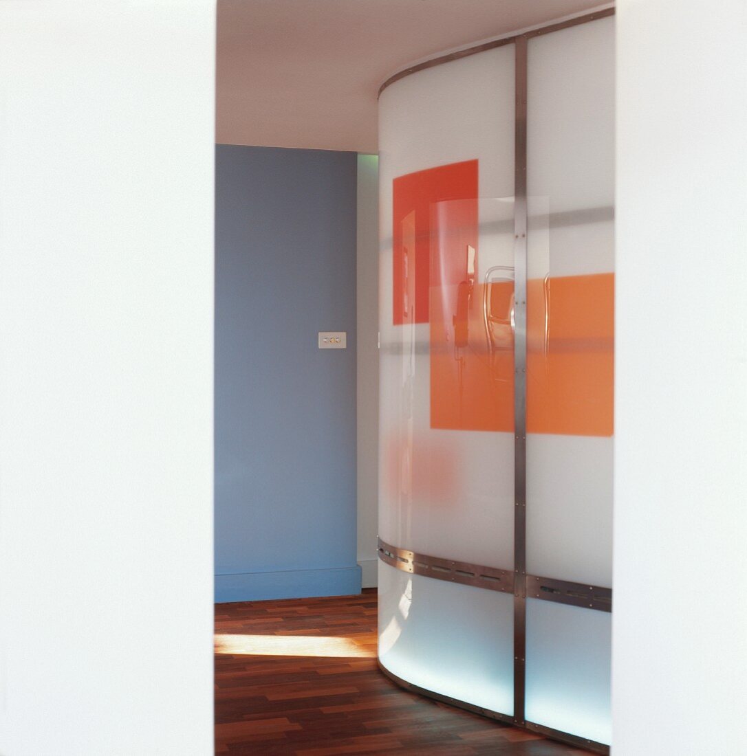 Curved, illuminated glass wall with coloured blocks in foyer