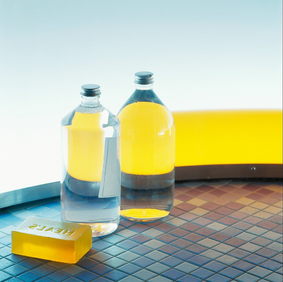 Full bottles and yellow soap on mosaic floor tiles