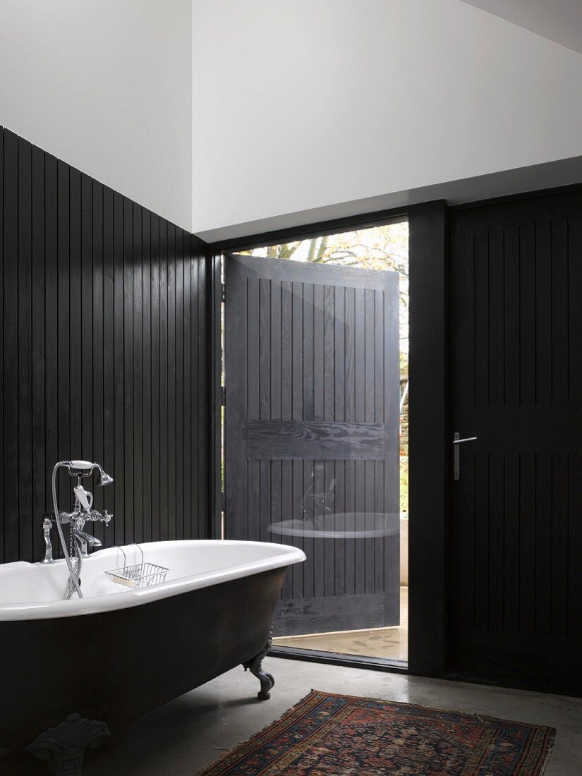 Vintage Badezimmer mit teilweise schwarzer Holzverkleidung und raumhohem Fenster mit halbgeschlossener Türlade