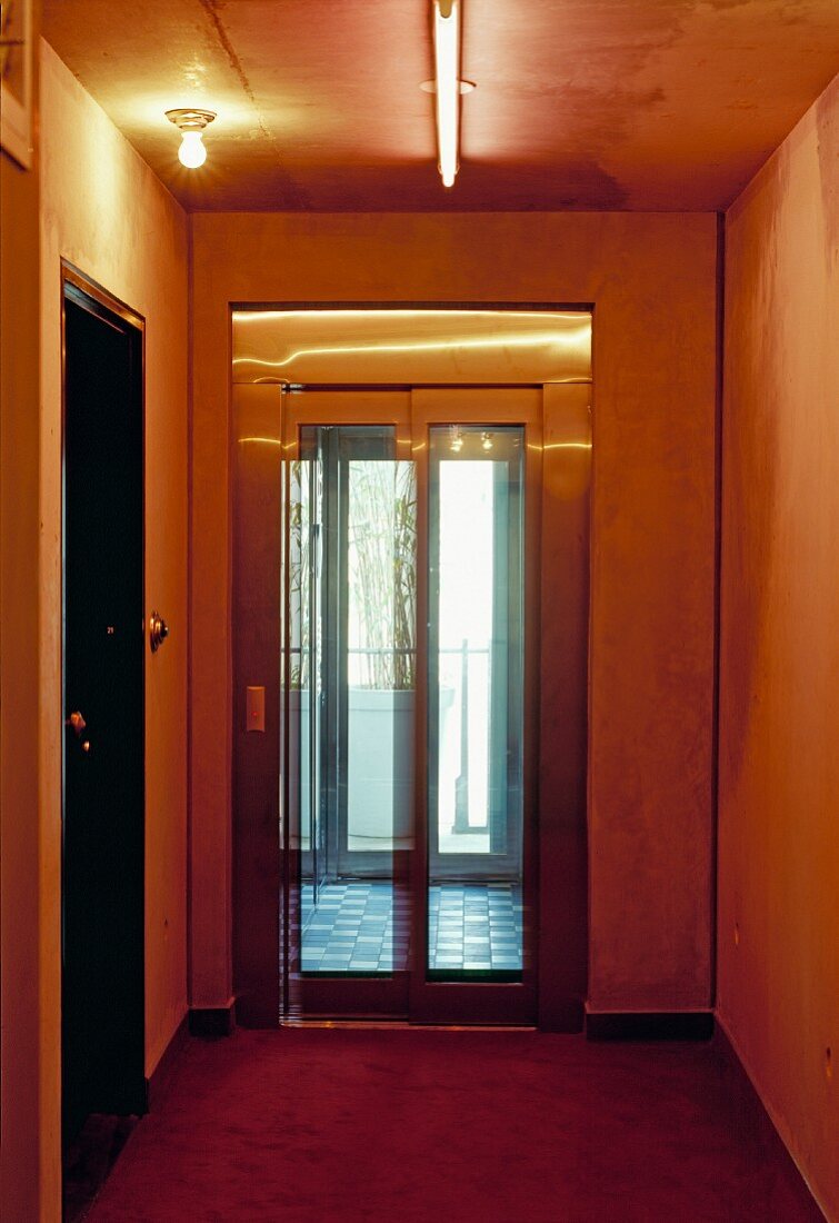 Traditioneller gelb getönter Flur mit modernem verglasten Lift