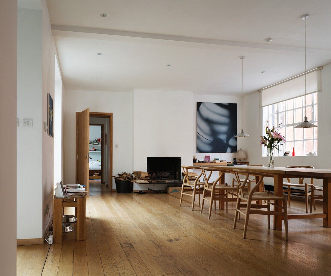 Loftartiger Wohnraum mit Esstisch und Klassikerstühlen auf hellem Dielenboden