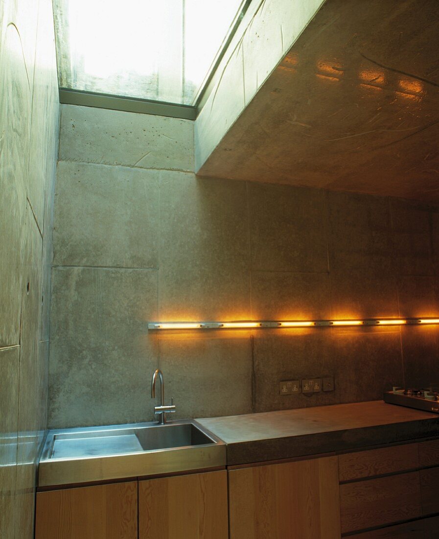 Corner of contemporary kitchen with fluorescent tubes on concrete block wall