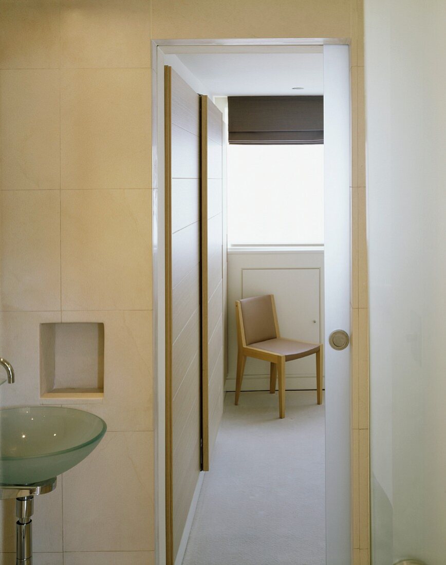Modernes Badezimmer mit offener Schiebetür und Blick auf Stuhl