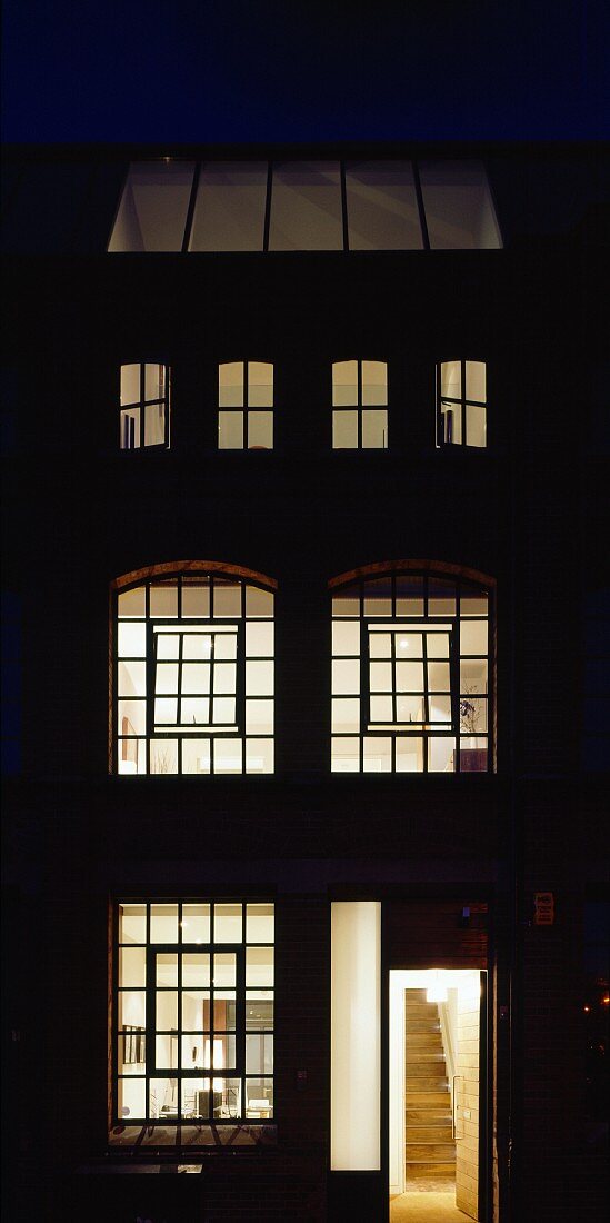 Englisches Wohnhaus mit beleuchteten Sprossenfenstern in Nachtstimmung