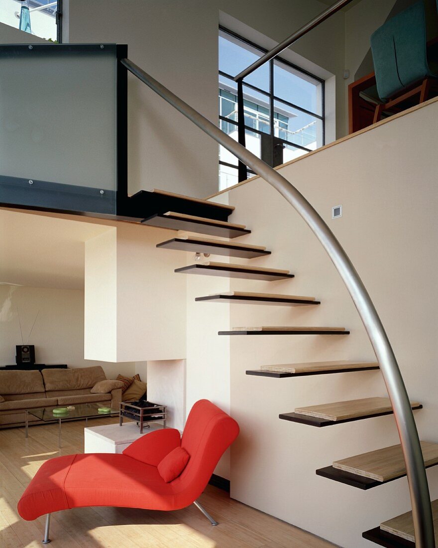 Freiauskragende Treppenstufen an Wand im Wohnraum mit roter Chaiselongue