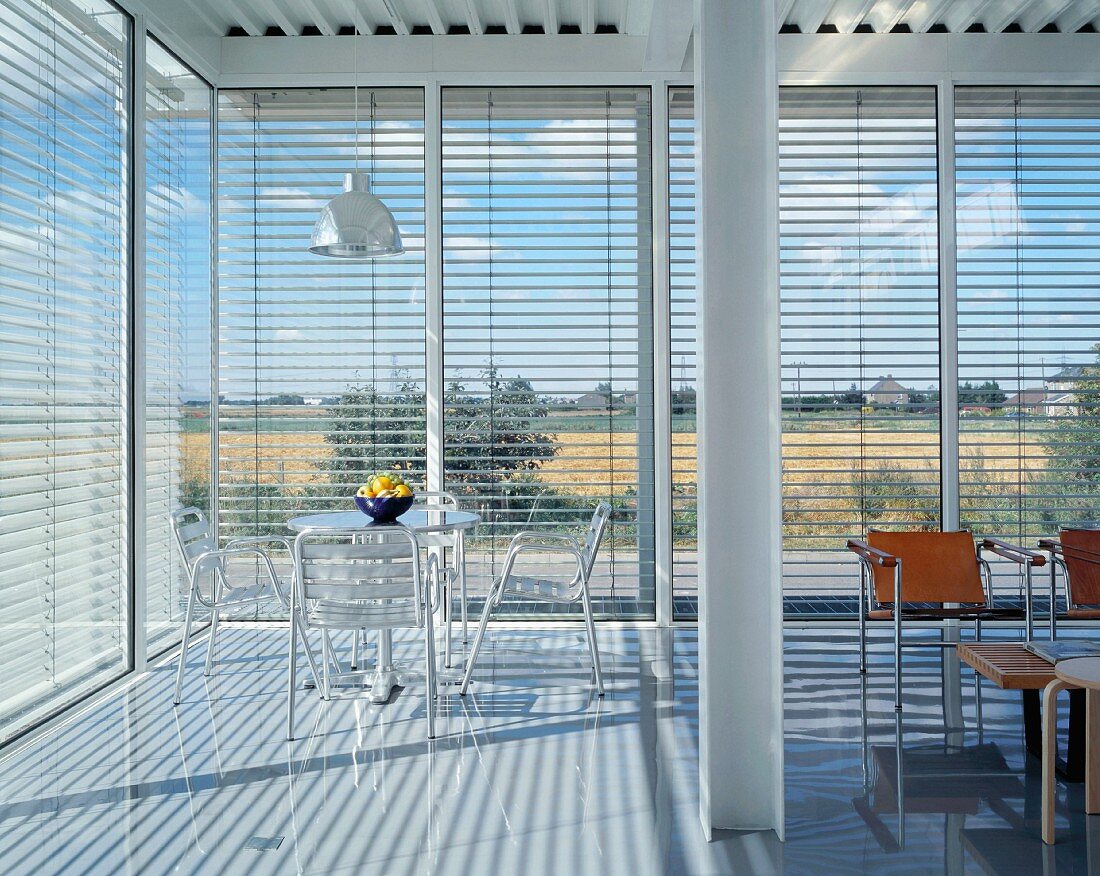 Offener moderner Wohnraum mit Panoramafenster und halbgeschlossener Jalousie
